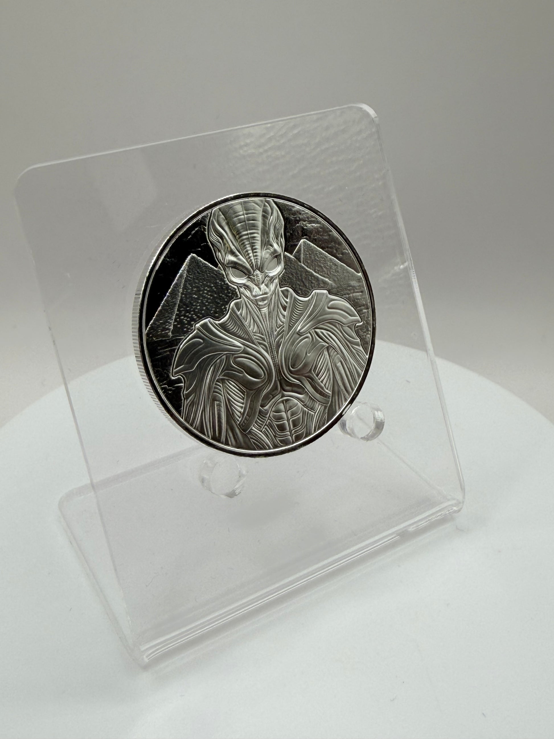 Futuristic alien silver coin with pyramid background artwork
